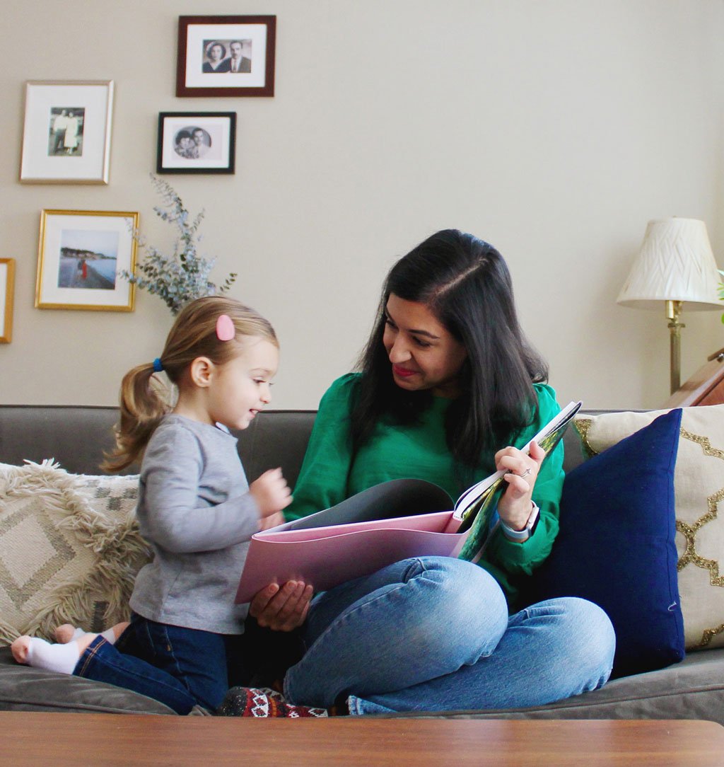 Mother and daughter sitting on a couch while looking at a photo book