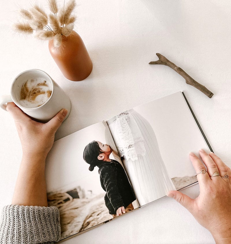 Woman’s hands holding a cup of coffee and a photo book