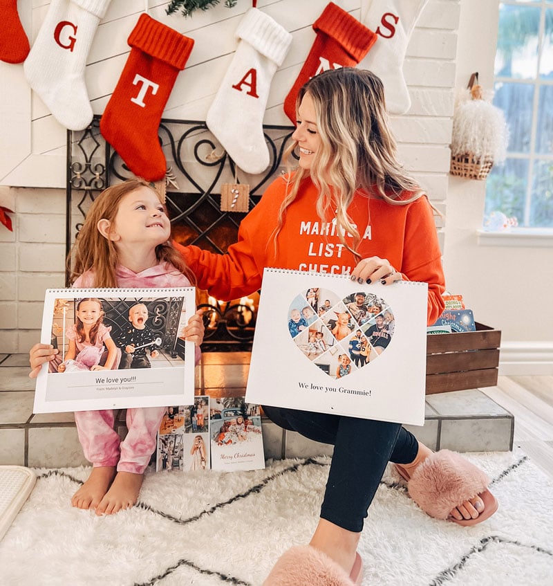 Mother and daughter sitting on fireplace with photo calendars