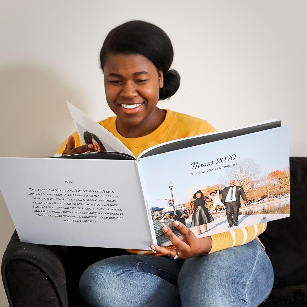 Woman looking at and holding a hardcover photo book